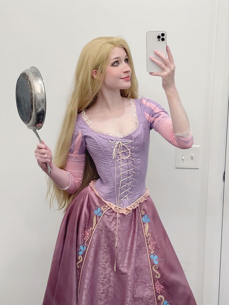 a woman in a purple dress taking a selfie with a mirror and cell phone