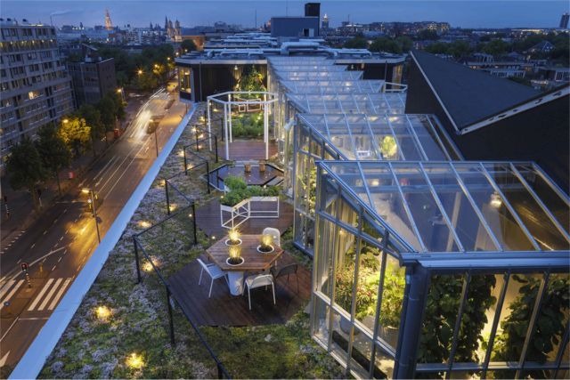 an aerial view of a rooftop garden and patio area at night with the city lights on