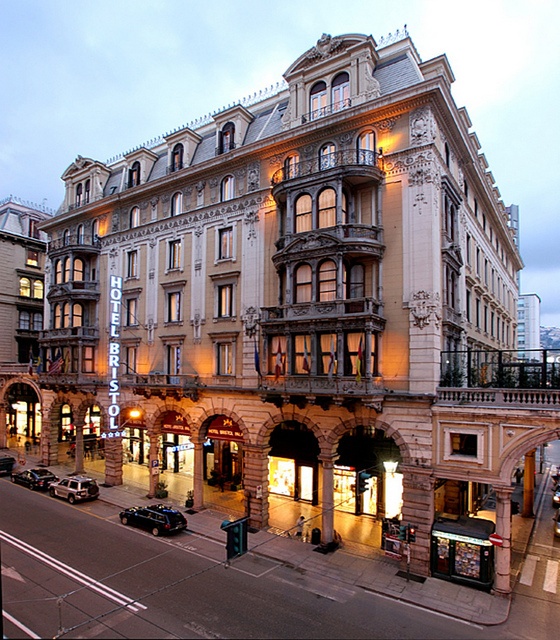 an old building is lit up at night on the corner of a street with cars parked in front