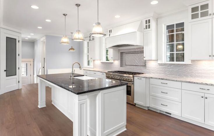 a large kitchen with white cabinets and black counter tops, along with an island in the middle