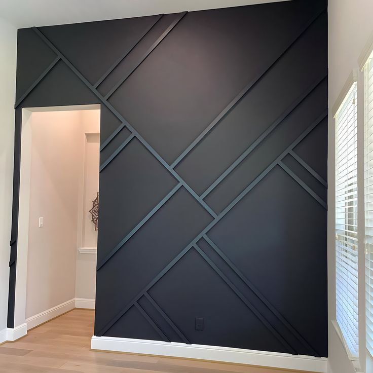 an empty room with wood floors and black wall covering the entire area, including shutters