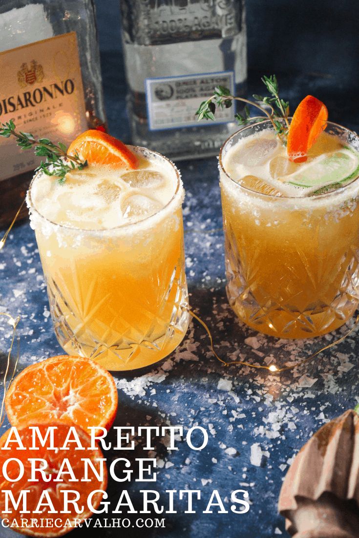 two glasses filled with orange margaritas on top of a table