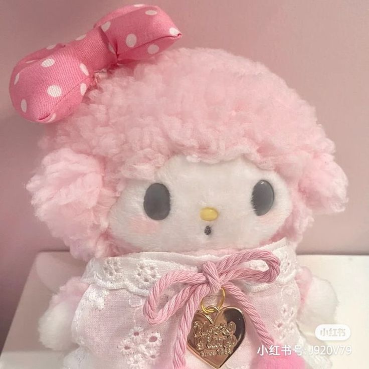 a hello kitty stuffed animal with a pink bow on it's head sitting on a table