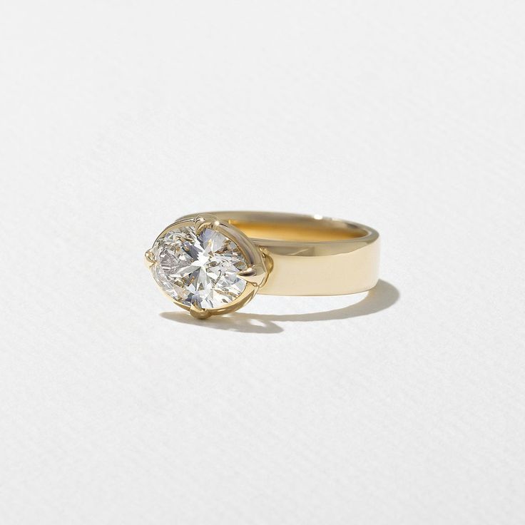 a yellow gold ring with a single diamond in the center on a plain white surface