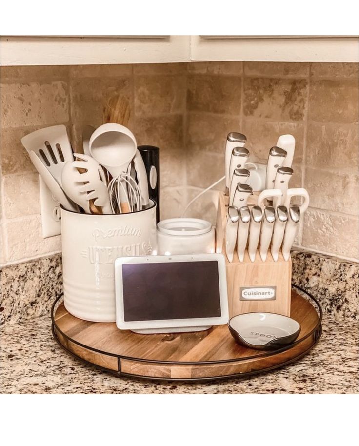 kitchen utensils are arranged on a wooden tray in the corner of a counter