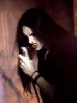 a woman with long black hair holding a cell phone up to her face while standing in front of a curtain