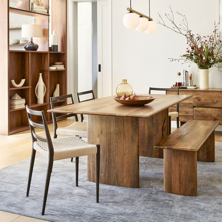 a dining room table with two benches in front of it and an area rug on the floor