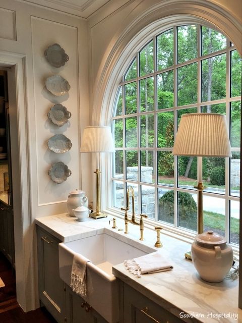 a kitchen with an arched window, sink and lamp in front of the countertop