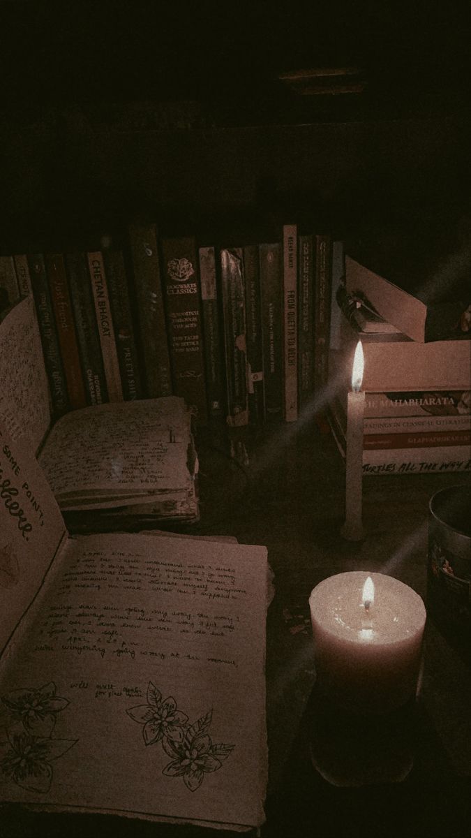 an open book sitting on top of a table next to a candle and some books