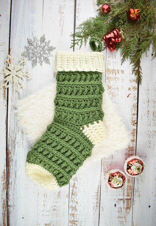 a knitted christmas stocking hanging on a wooden wall next to ornaments and decorations