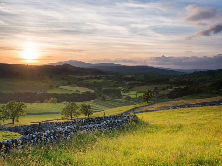 the sun setting over rolling hills and fields