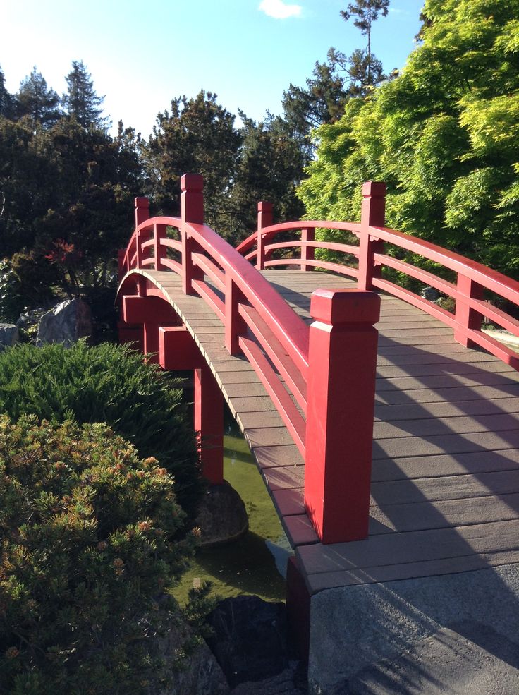 a red wooden bridge over a small pond