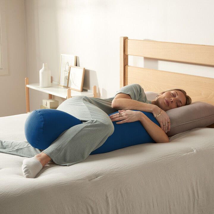 a woman laying on top of a bed with her arms around the back of it