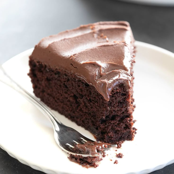 a piece of chocolate cake on a white plate with a fork in front of it