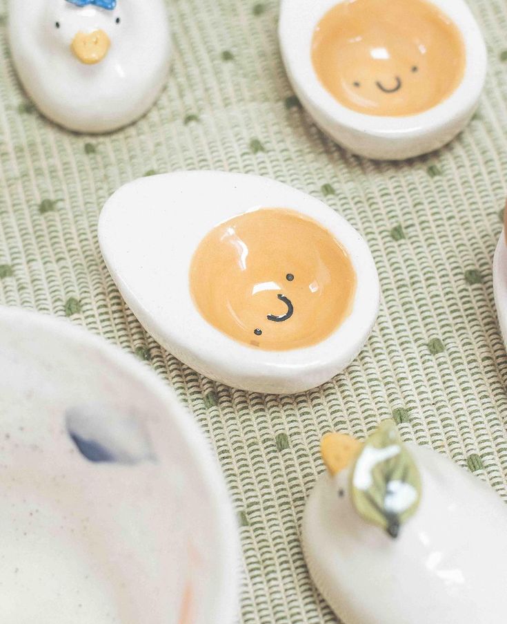 small ceramic bears are sitting on the table next to eggs with faces painted on them