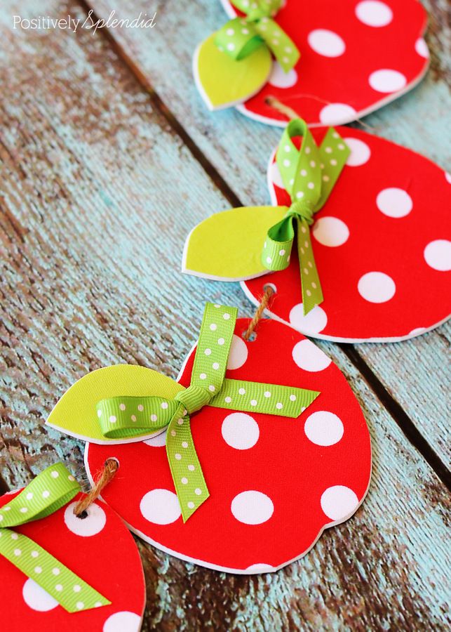 some paper strawberries are hanging on a wooden table with polka dots and green ribbons