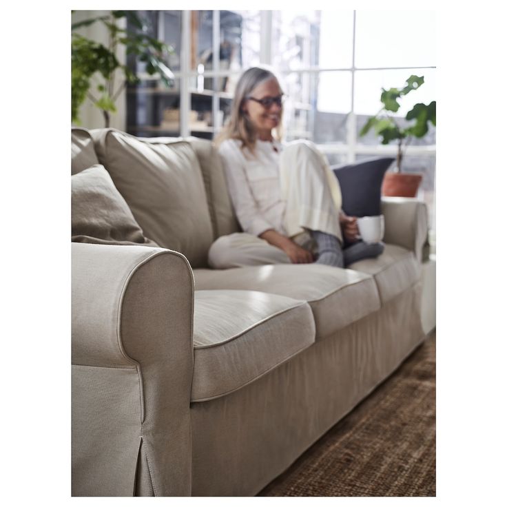 a woman sitting on top of a couch holding a laptop computer