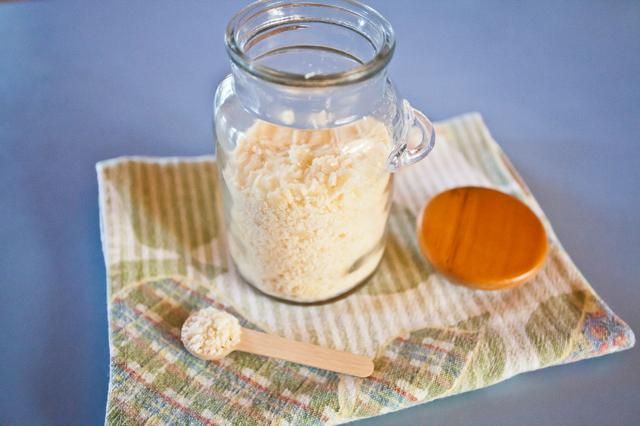 a glass jar filled with rice sitting on top of a table next to a wooden spoon