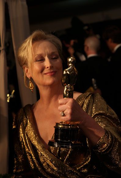 a woman holding an oscar statue in her hand