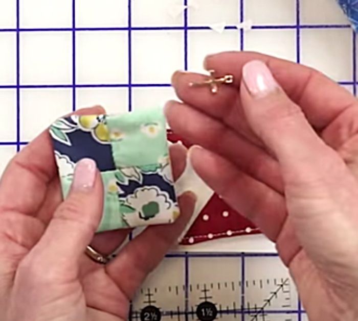 two hands are holding small fabric pieces in front of a ruler and measuring the length