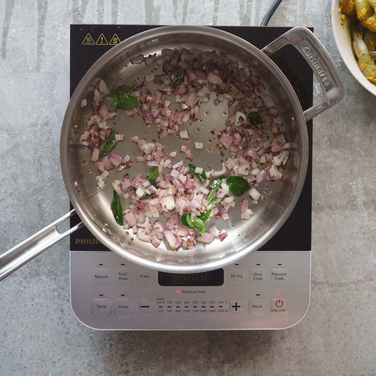 a pan filled with chopped onions on top of a stove next to a bowl of vegetables