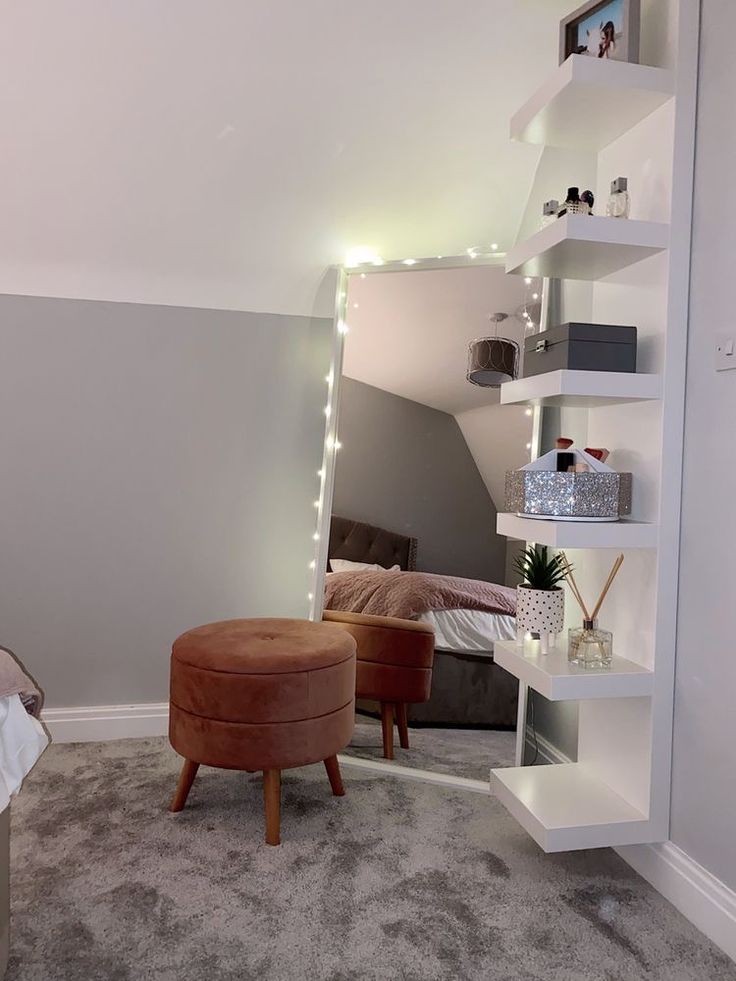 a room with a bed, chair and shelves in it's corner area that has lights on the ceiling