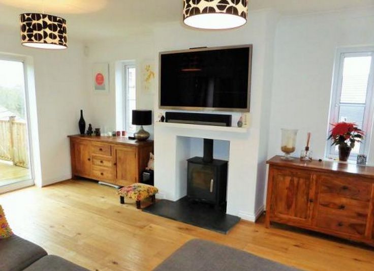 a living room filled with furniture and a flat screen tv mounted on the wall above a fire place