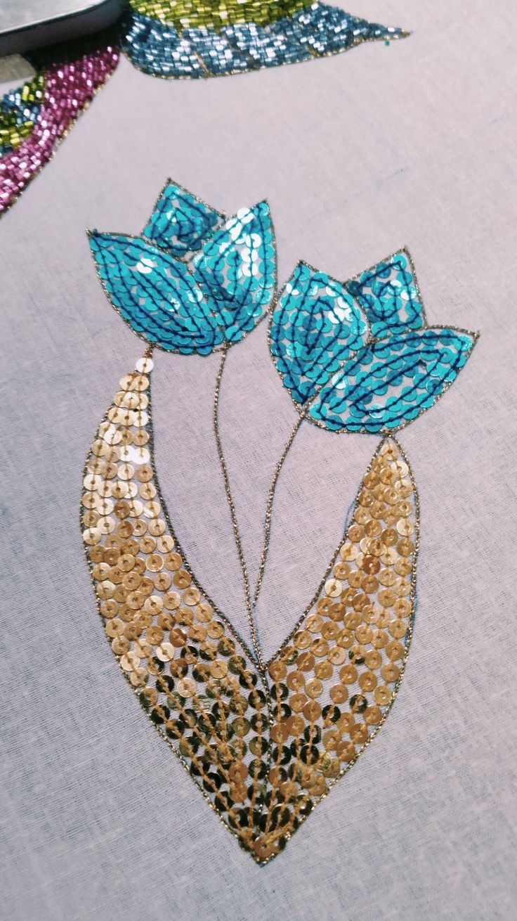 some sequins are on top of fabric with flowers and leaves in the middle