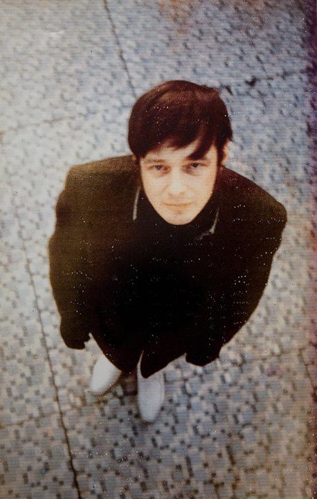 a young man sitting on the ground looking up at the camera with his eyes closed