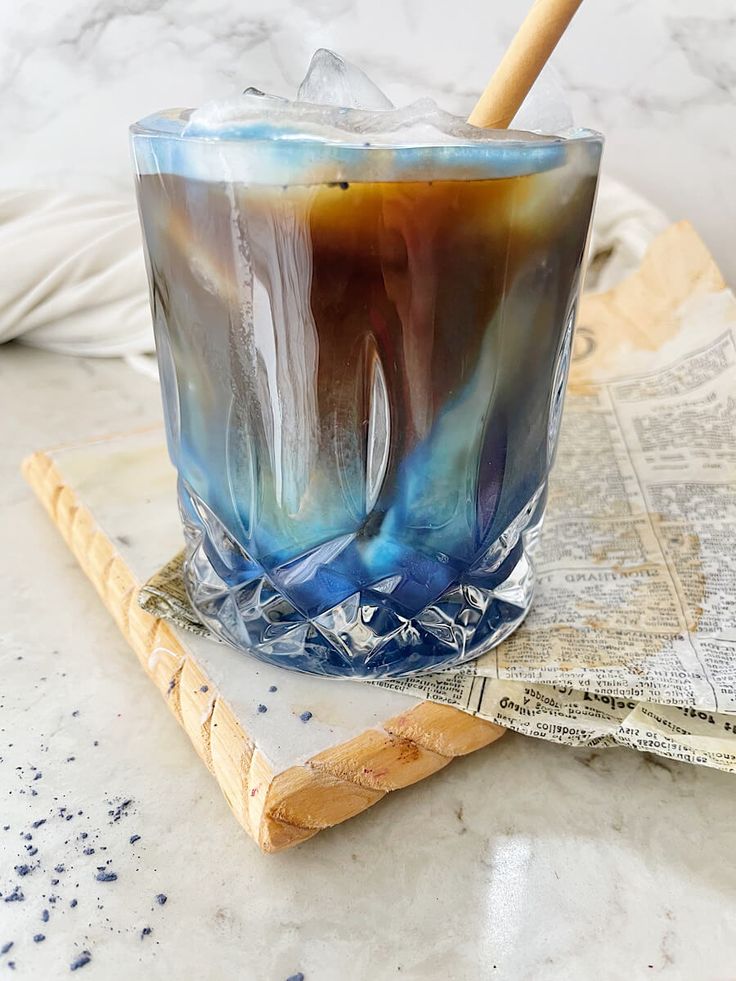 there is a glass with some liquid in it on the table next to a newspaper