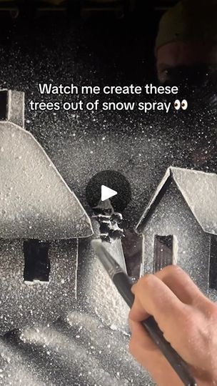 a man is using scissors to cut out the roof of a house that has snow on it