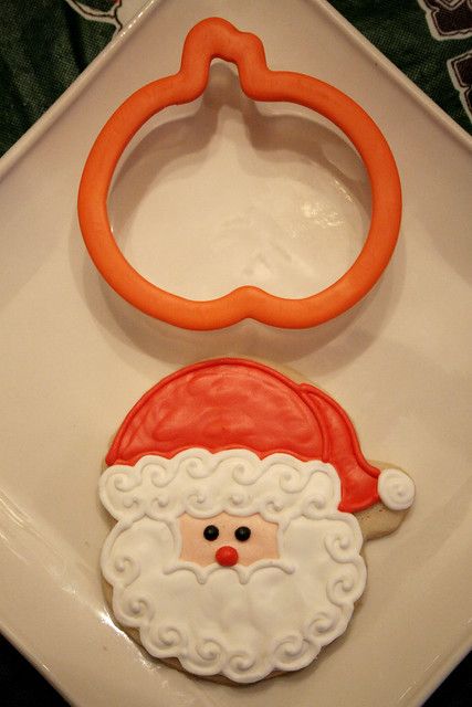 a cookie shaped like santa claus on a white plate with an orange ring in the middle