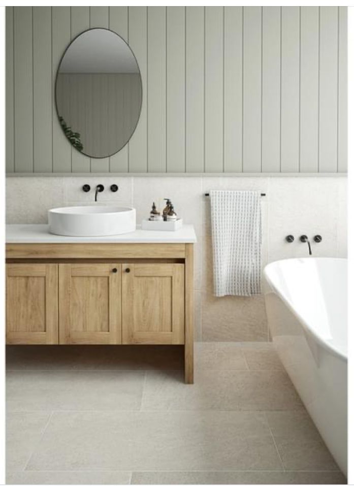 a bathroom with two sinks and a bathtub in the corner, along with a round mirror on the wall