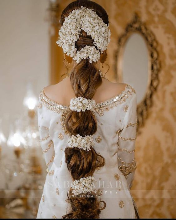 a woman with flowers in her hair wearing a white dress