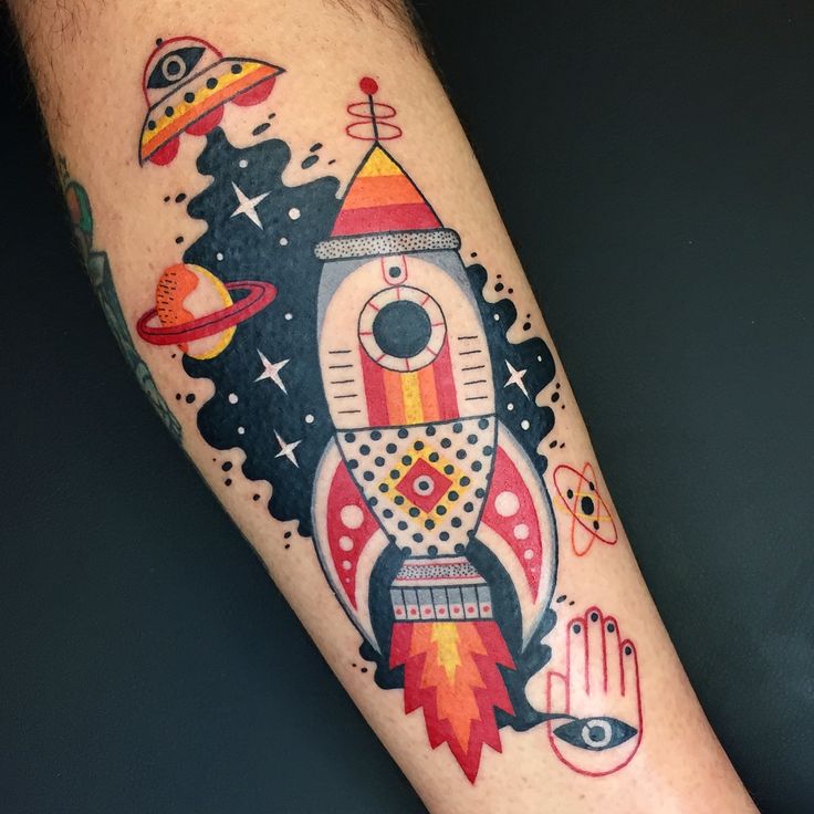 a colorful tattoo on the arm of a man with space and rockets around him,