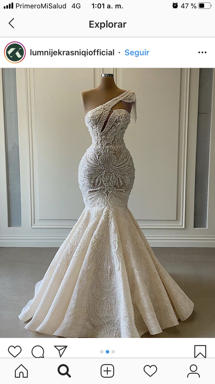 a white dress on display in front of a mannequin headdress with an embellishment