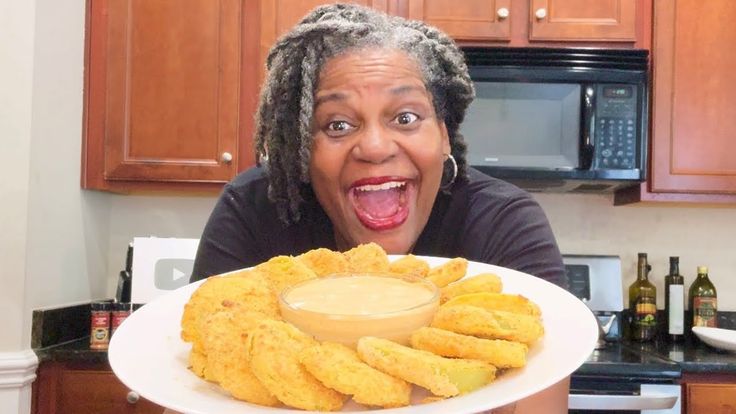 a woman with her mouth wide open holding up a plate of fried chicken nuggets