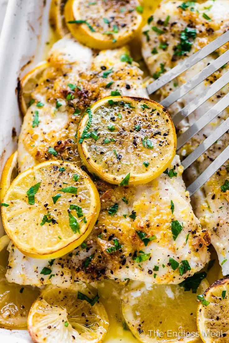 a pan filled with chicken covered in lemons and herbs