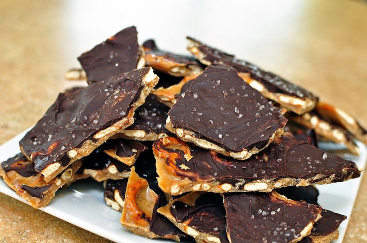 a white plate topped with pieces of chocolate covered in nuts and caramels on top of a table