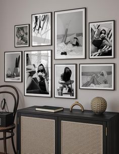 black and white photographs hang on the wall above an entertainment center with wicker furniture