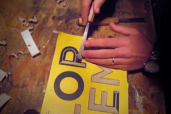 a person cutting up a piece of paper with scissors on a wooden table in front of them