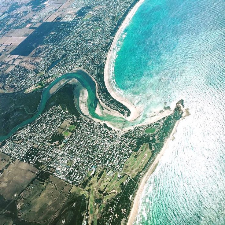 an aerial view of the ocean and coastline from above, with blue water in the foreground