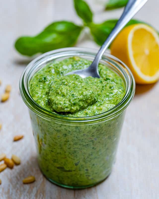 a spoon in a jar filled with green pesto