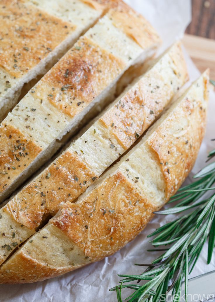 sliced loaf of bread sitting on top of a piece of wax paper next to a sprig of rosemary