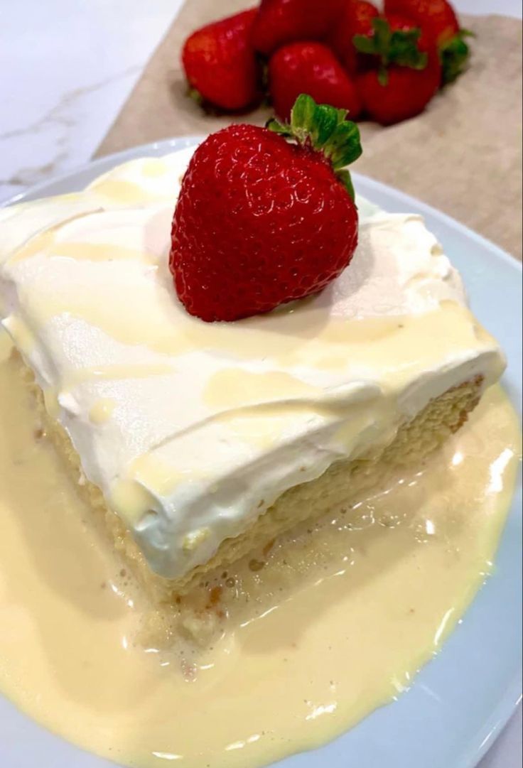 a piece of cake with white frosting and strawberries on top