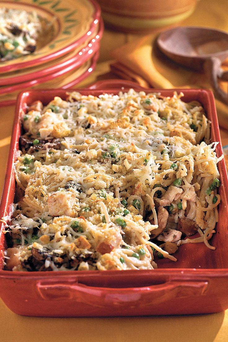 a red casserole dish filled with pasta and vegetables on a yellow tablecloth