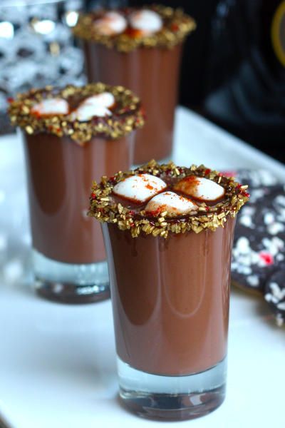 three glasses filled with chocolate desserts sitting on top of a white plate next to cookies