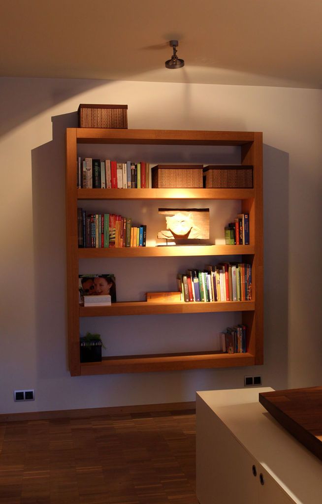 a book shelf with several books on it in the corner of a room next to a window