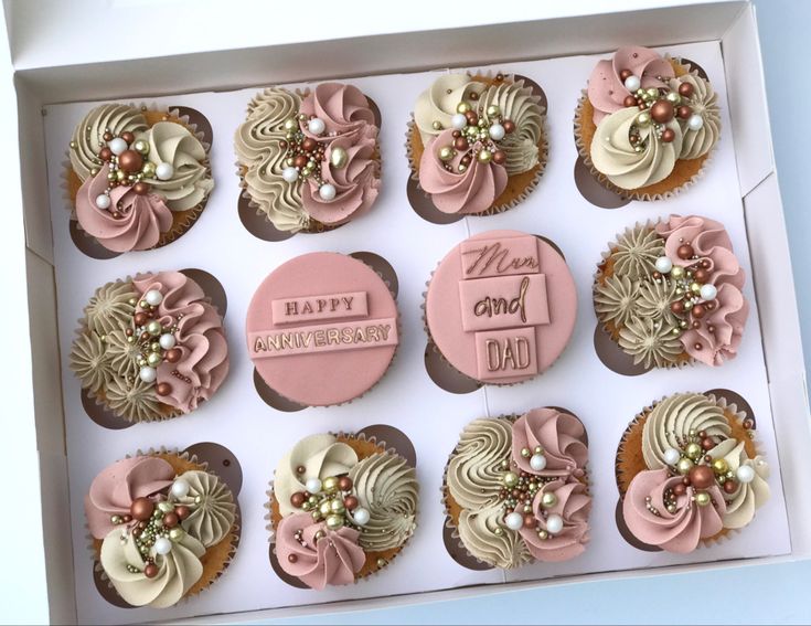 a dozen cupcakes in a box decorated with pink and white frosted decorations