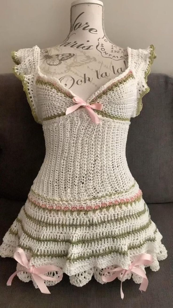 a dress made out of crochet with pink bows on the front and bottom